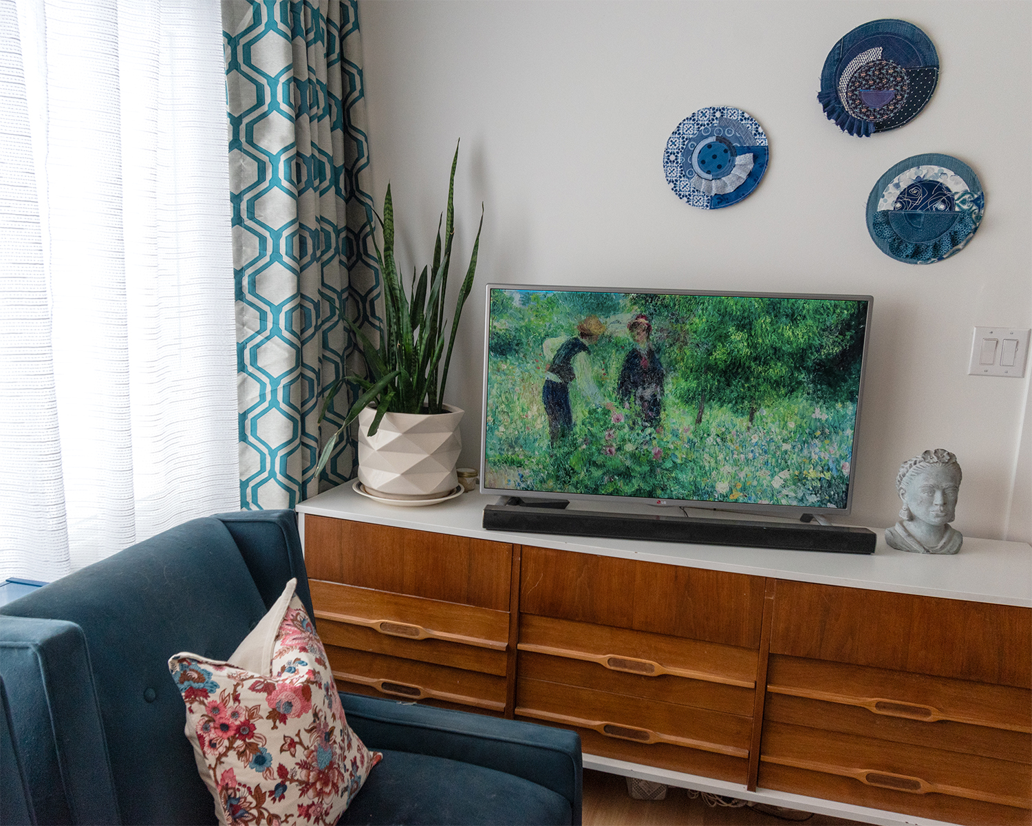 3 pieces of textile wall art above a TV in a midcentury room.